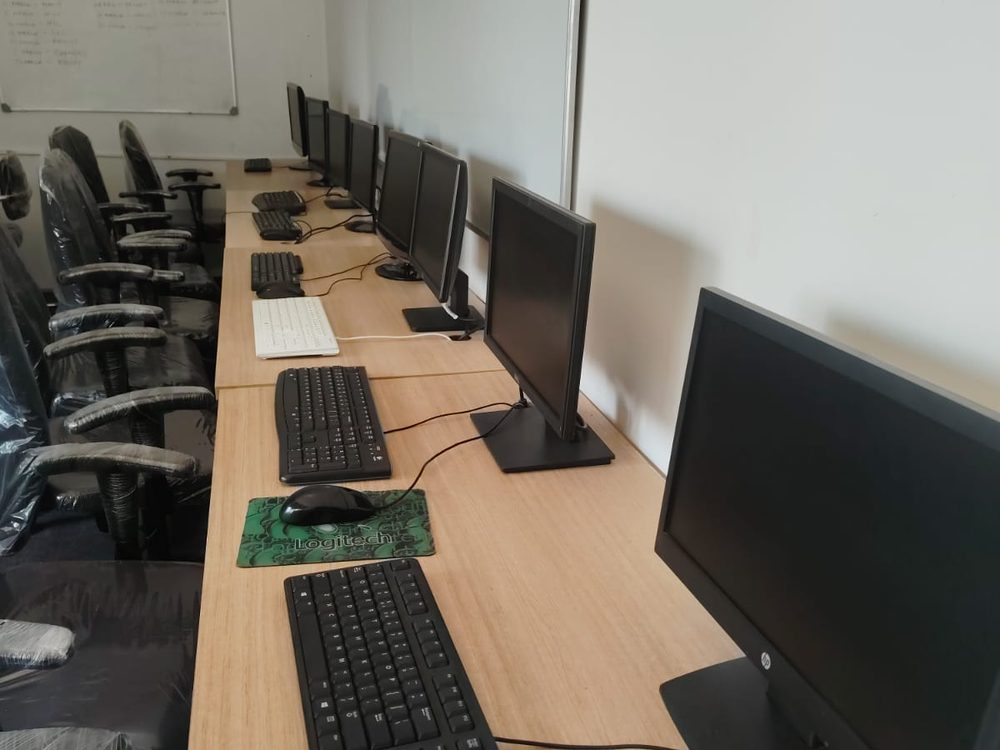 Monitors, keyboards and mice laid out along the training bench beside a whiteboard.